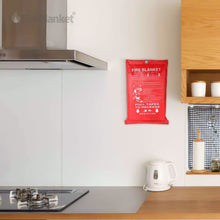 Fire Blanket, Red fire blanket mounted on a white kitchen wall near a kettle and stove with wooden cabinets above.